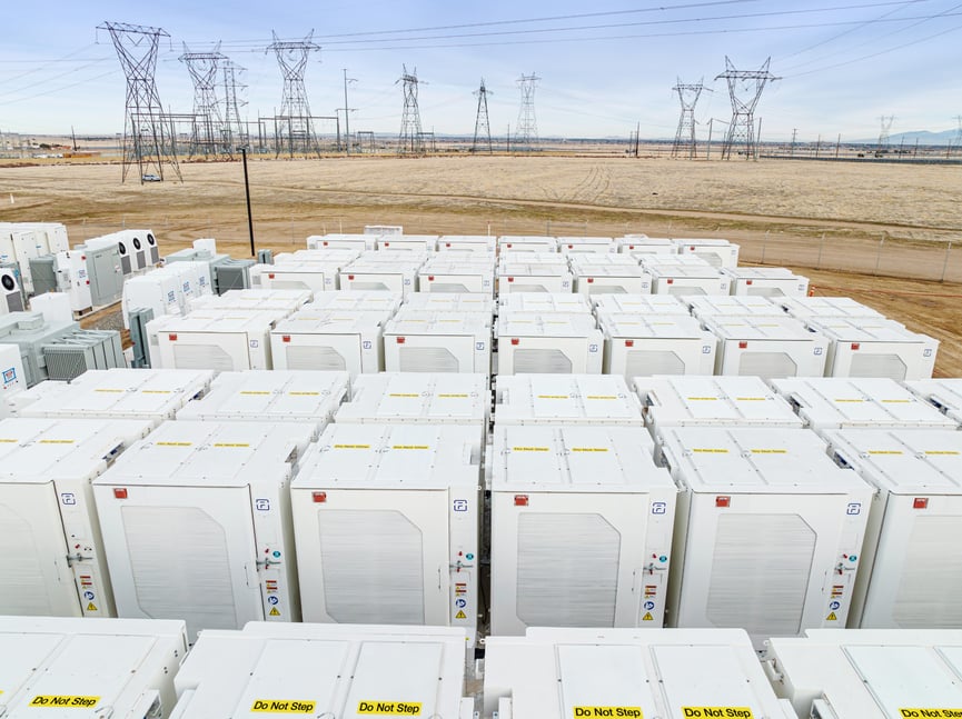 Fluence Gridstack cores lined up in field with energy utility lines in the background