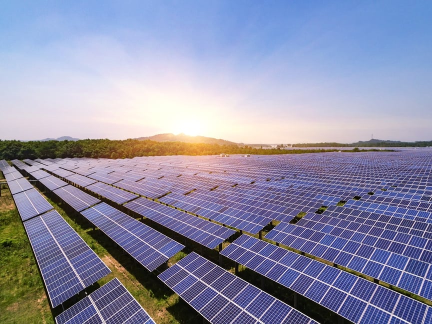 Solar panels in a field with the sun rising over the horizon